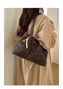 Detail of vintage brown tote bag with beaded ornament on casual beige coat