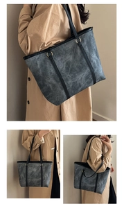 Three-way view of a large dark grey tote bag with black handles and gold hardware