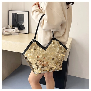 Close-up of golden sequin tote bag featuring black leather handles and V-shaped opening