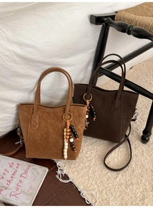 Detail of suede bucket bags with wooden bead tassels and dual shoulder straps