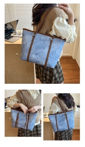 Detail of blue denim tote bag with brown leather handles and smooth zipper closure