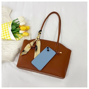 Large brown leather tote bag detail with decorative floral scarf and phone for scale