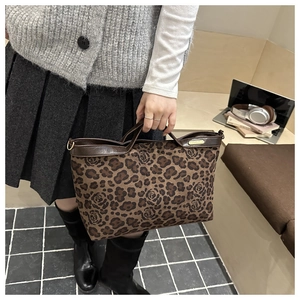 Detail of leopard print tote bag with brown leather handles and golden metal hardware