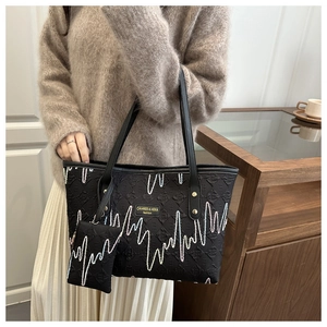 Detail of black tote bag with heart pulse embroidery and mini matching pouch attachment