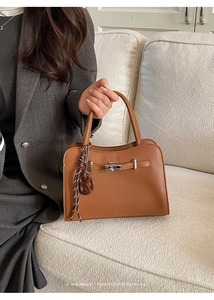 Close-up of brown litchi leather bag with silver twist lock and decorative silk scarf