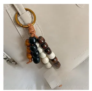 Macro detail of wooden bead pendant accessory with bronze ring attached to a bag