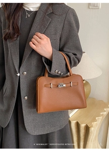 Macro view of caramel brown pebbled leather texture with silver twist lock and wavy edge