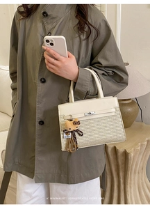 Close-up of retro woven leather handbag with silver lock and plush cat charm