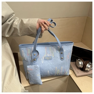 Detail of light blue tote bag with colorful wave embroidery and matching mini pouch