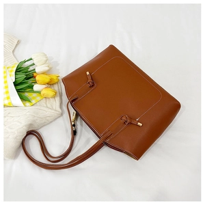Flat lay of brown caramel tote bag with white stitching on a soft fabric backdrop