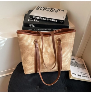 Detail of tan textured fabric tote bag with leather straps and gold metal ring accents