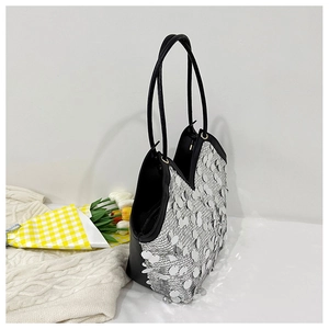 Detailed view of silver sequin tote bag with black straps on a soft knit background