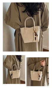 Detail view of beige bucket bag with unique beaded tassel and slim shoulder strap