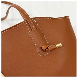 Macro shot of contrast stitching and gold hardware on a brown tote bag strap