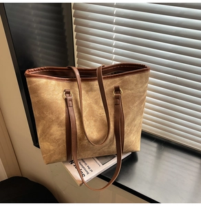 Detail of a large tote bag featuring vintage matte khaki texture and gold ring hardware