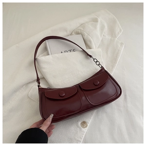 Gros plan sur le sac baguette bordeaux avec doubles poches avant et bandoulière en chaîne