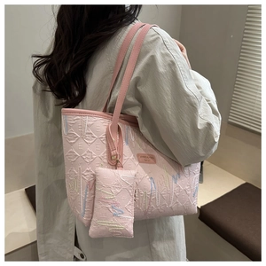 Close-up of pink tote bag featuring quilted letter patterns and detailed colorful embroidery