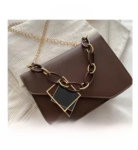 Close-up of brown leather bag with golden geometric clasp and mixed metal chain straps