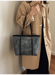 Detail of grey marble texture tote bag with black leather handles and gold metal rings