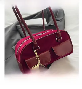Detail of burgundy velvet baguette bag with patent leather pockets and cherry charm