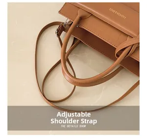 Détail du sac marron avec gaufrage crocodile, lettrage doré et bandoulière réglable