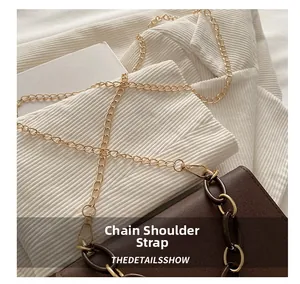 Detail of a brown leather bag with a gold metal chain and dark brown acrylic ring strap