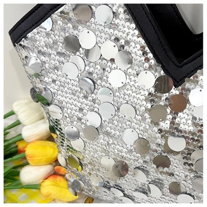 Close-up of sparkling silver sequins and black leather trim on a stylish tote bag