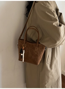 Detail of dark brown suede bucket bag with beaded tassel and detachable shoulder strap
