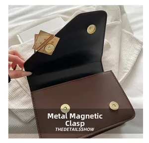 Detail showing the golden magnetic snap button closure on a brown leather handbag