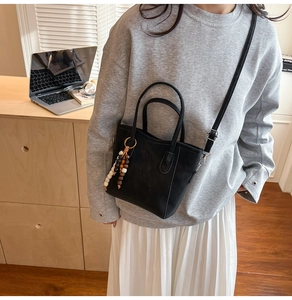 Detail of black suede bucket bag with vintage beaded tassel and slim shoulder strap