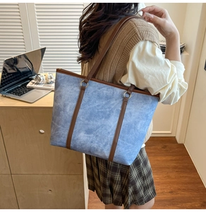 Detail of blue textured tote bag with brown shoulder straps in office setting