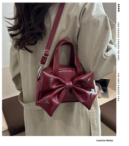 Dettaglio della borsa bordeaux con fiocco e stelle in metallo sopra un trench beige classico