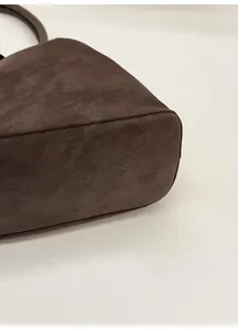 Detail view of the thickened bottom support and reinforced stitching on a brown tote bag