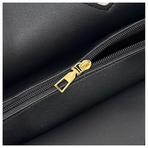 Detailed macro view of the premium golden metal zipper on black lychee textured leather bag