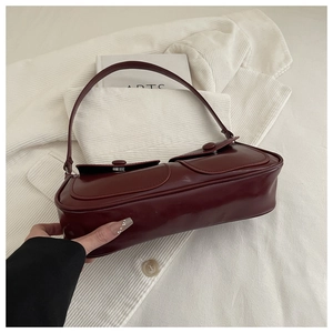 Détail du sac sous le bras vintage rouge foncé avec deux poches à rabat et cuir brillant