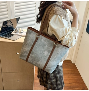 Macro shot of large grey tote bag with brown leather handles and premium matte texture