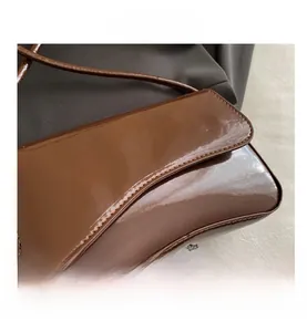 Close-up of deep brown patent leather handbag with glossy mirror finish and curved bottom