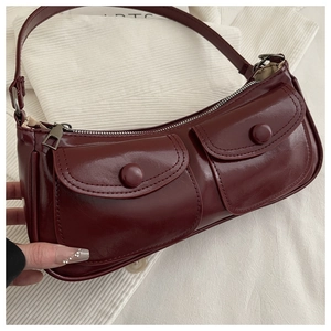 Detail of burgundy patent leather baguette bag featuring front pockets and silver hardware