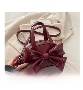 Dettaglio della borsa rosso vino con un grande fiocco e rivetti metallici a forma di stella
