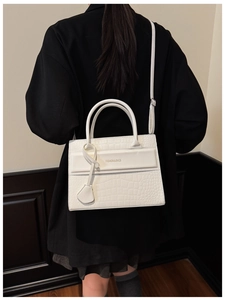 Close-up of a white stone pattern handbag featuring adjustable strap and fashion print