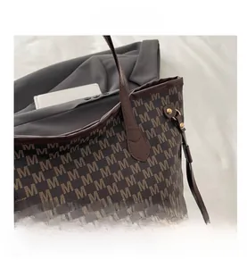 Detail of monogram M print tote bag with brown leather handles and gold metal hardware