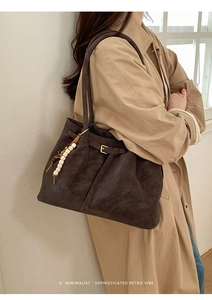 Detail of dark brown tote bag with wooden bead charm and long shoulder strap