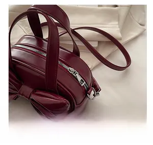 Dettaglio della borsa in pelle bordeaux con grande fiocco e ciondoli a stella scuri