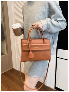 Détail d'un sac à main marron à motif croco montrant la texture et le logo de mode