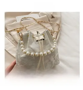 Détail de la broderie papillon en dentelle blanche et de l'anse en perles du sac seau