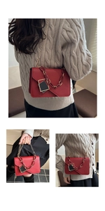 Detail of red leather crossbody bag featuring gold chain strap and enamel pendant