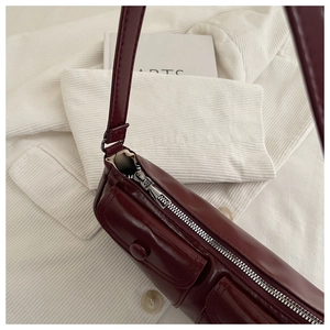 Detail of wine red glossy leather shoulder bag with pockets and silver zipper