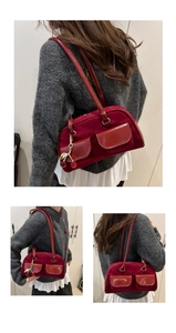 Detail of red vintage shoulder bag with dual pockets and cherry charm decoration