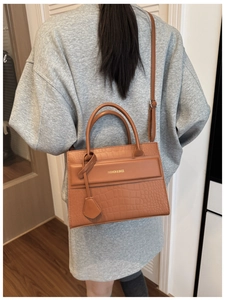 Close-up of caramel crocodile embossed faux leather crossbody bag with dual handles