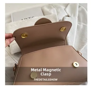 Details der goldenen Magnetschnalle und Lederklappe an einer hellbraunen Satteltasche